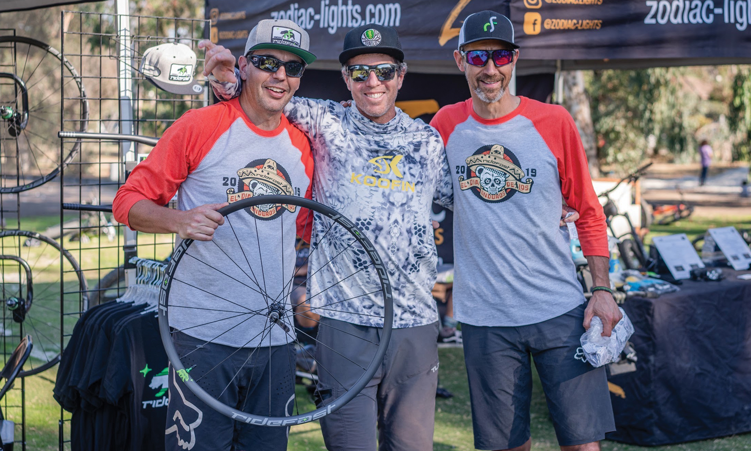 Three men holding a mountain bike tire