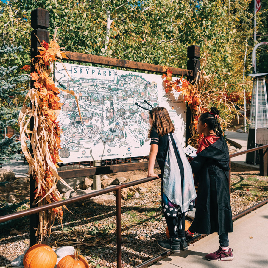 Two children in Halloween costumes look at the park map